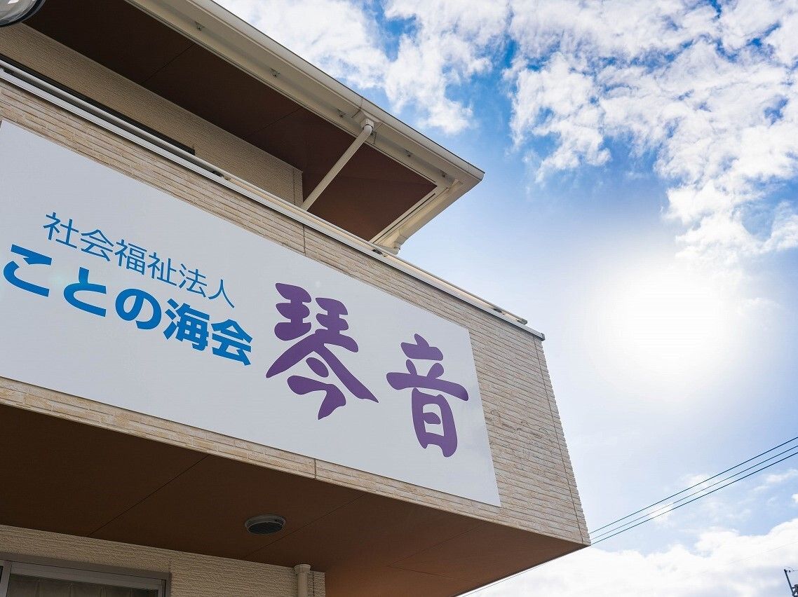 車いすの高齢女性が指さす方向を一緒に見て笑っているエプロンを付けた女性スタッフ。