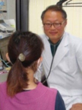 白衣を着て聴診器を付けている医師のような男性が髪を一つに結んでいる女性と向き合っている。