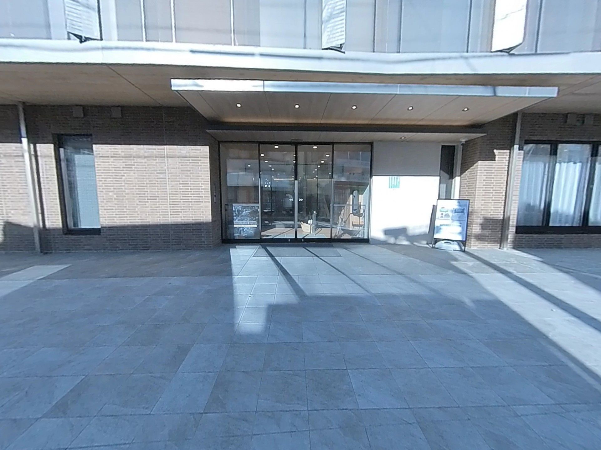 眼鏡をかけた高齢女性が車いすに座り、白衣を着た女性スタッフが笑顔で車いすを押している。