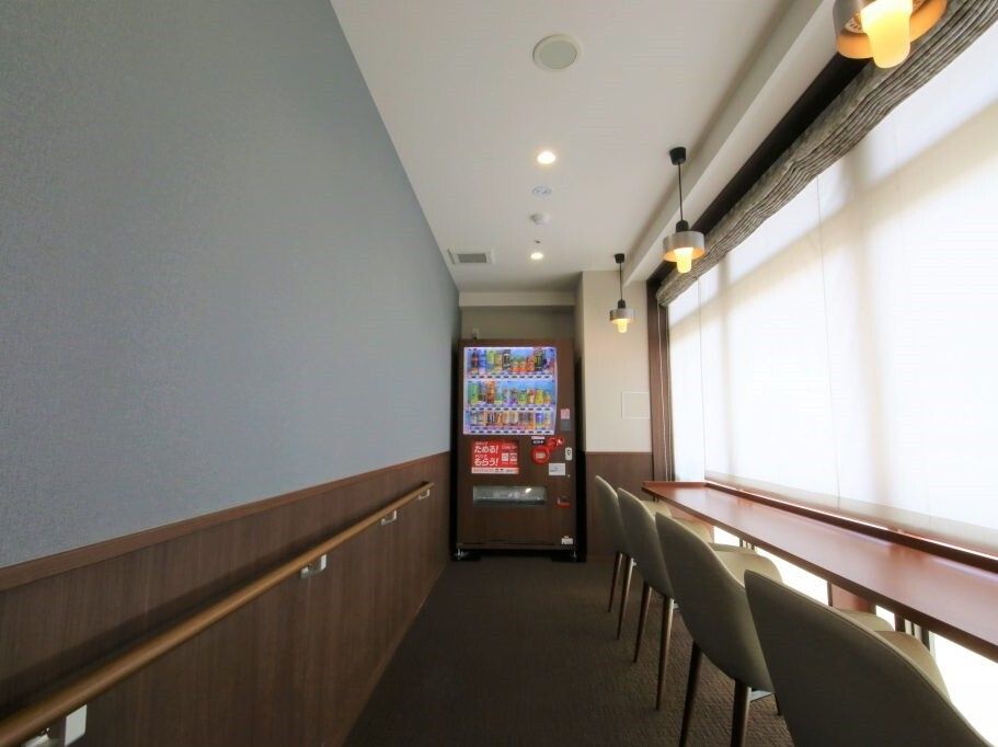 一番奥にはブラウンの自動販売機が付き、壁には手すりがあり、右側の窓際にはカウンター席がある。