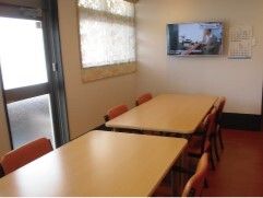 木製のテーブルセットが置かれたスペース。大きな窓があり、壁には壁掛けテレビが付いている。