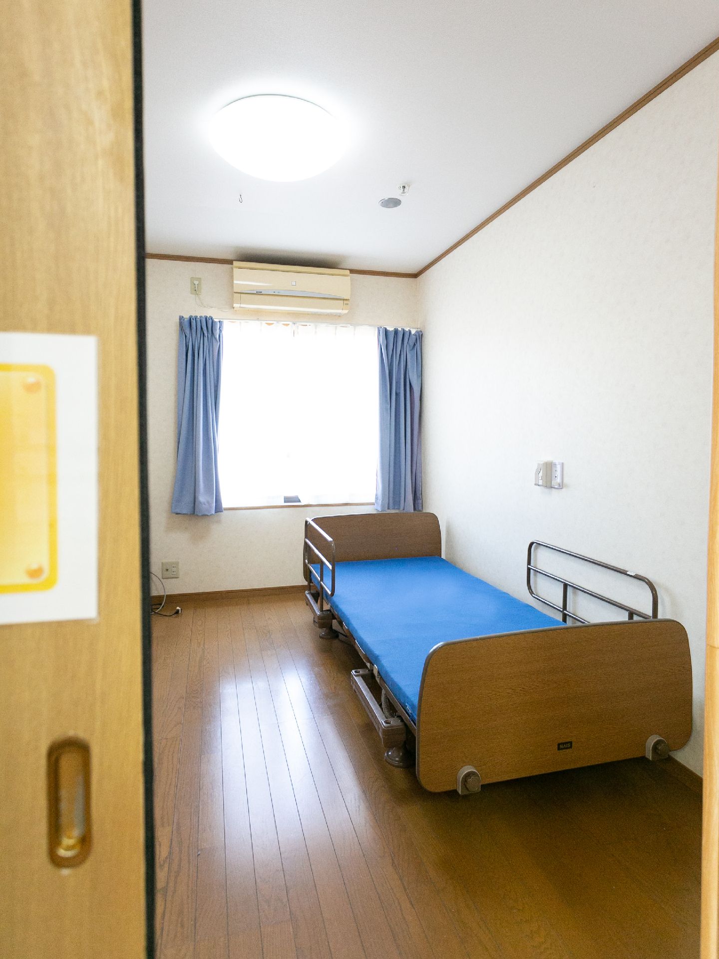 窓から日差しが入りベッドや棚などが設置されている居室