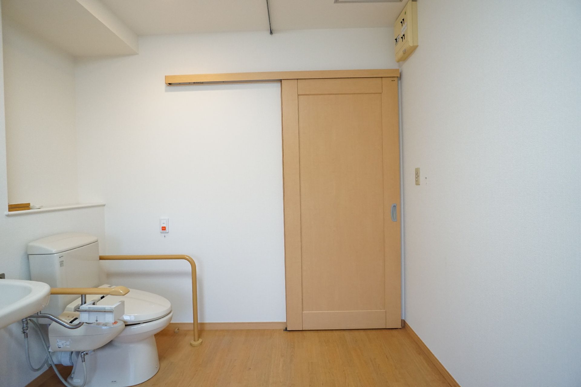 白い壁沿いにトイレと洗面台が設置された部屋