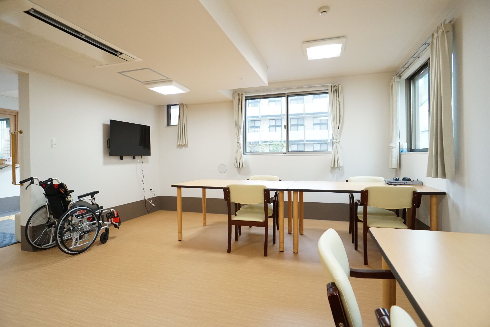 木製の机と椅子が置かれた窓がある白い壁の部屋