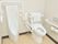 男性用の小便器が左側にあり、右側の様式のトイレには手すりと背もたれが付いている。