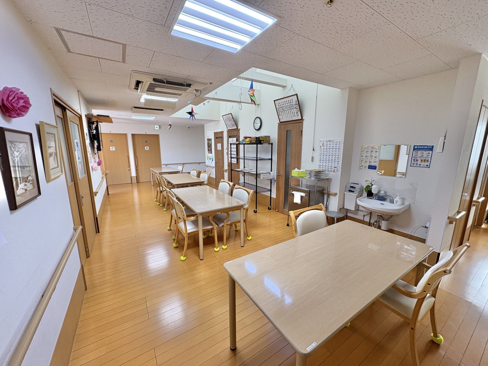 拍手をしながら何かを鑑賞しているピンクのポロシャツを着た若い女性スタッフと白髪の高齢女性。