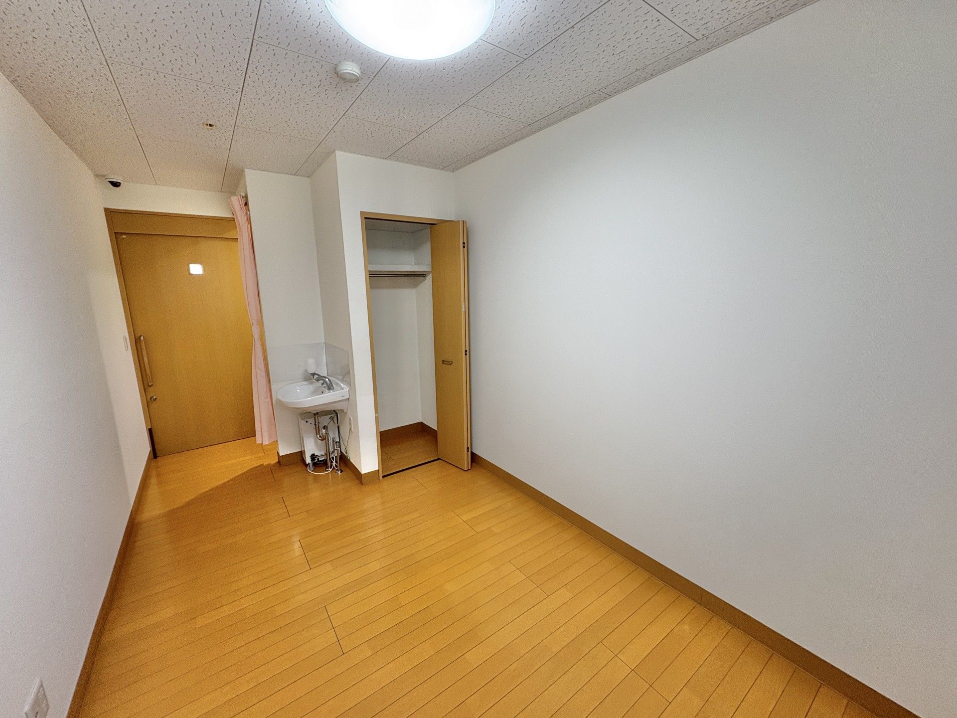 誰かに手を振っている車いすの高齢女性のそばにはエプロンを付けた女性スタッフがいて同じ方向を見ている。