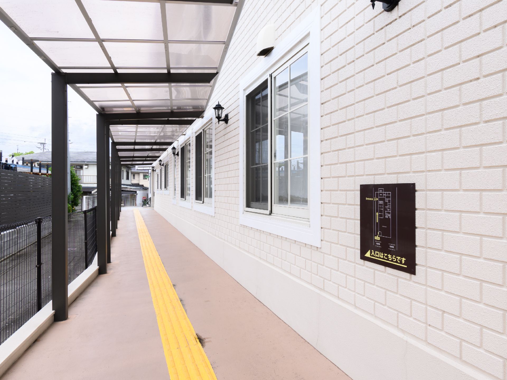 建物の側面に設けられた点字ブロックの敷かれた屋根のある通路