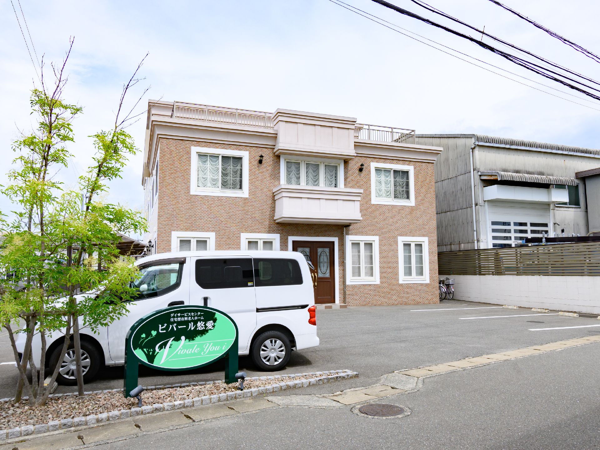 駐車場の奥に立地している２階建てのレンガ調の壁の建物