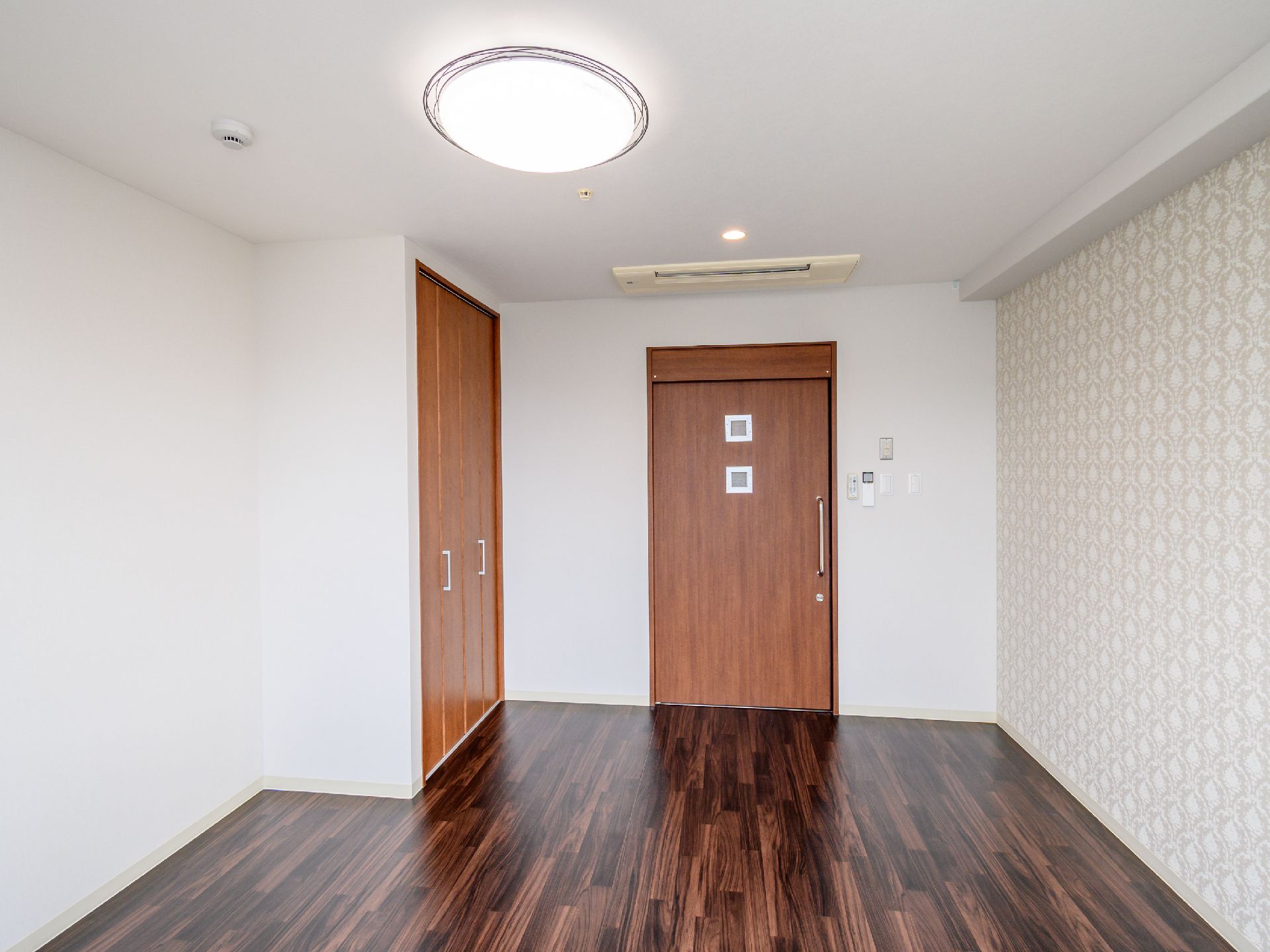 茶色の扉が付いた白い壁の何も置かれていない部屋