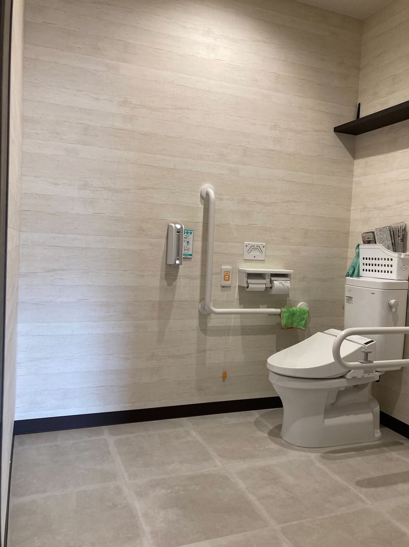 広々としたトイレ内にはシンプルな便座と手すり、呼び出しボタンが設置されている。