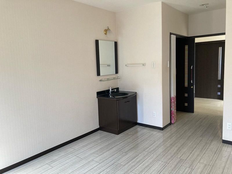 グレーがかったフローリングの部屋には収納スペース付きの洗面所があり、居室のドアはスライド式。