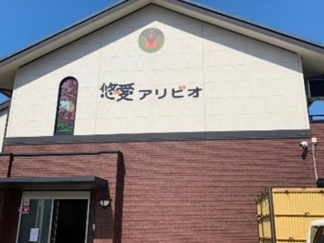2階建ての建物の1階部分の外壁はブラウン、2階部分の外壁は白で、ホーム名が書かれている。