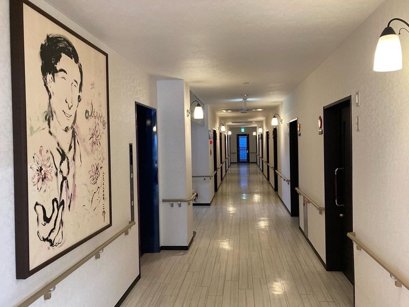 手すりが付いたまっすぐな廊下には男の人が描かれた大きな絵が飾られ、通路には何も置かれていない。