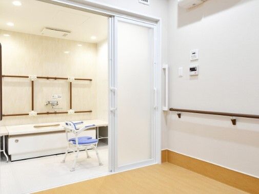 白を基調とした浴室と脱衣所にはダークブラウンの手すりがあり、シャワーチェアもある。