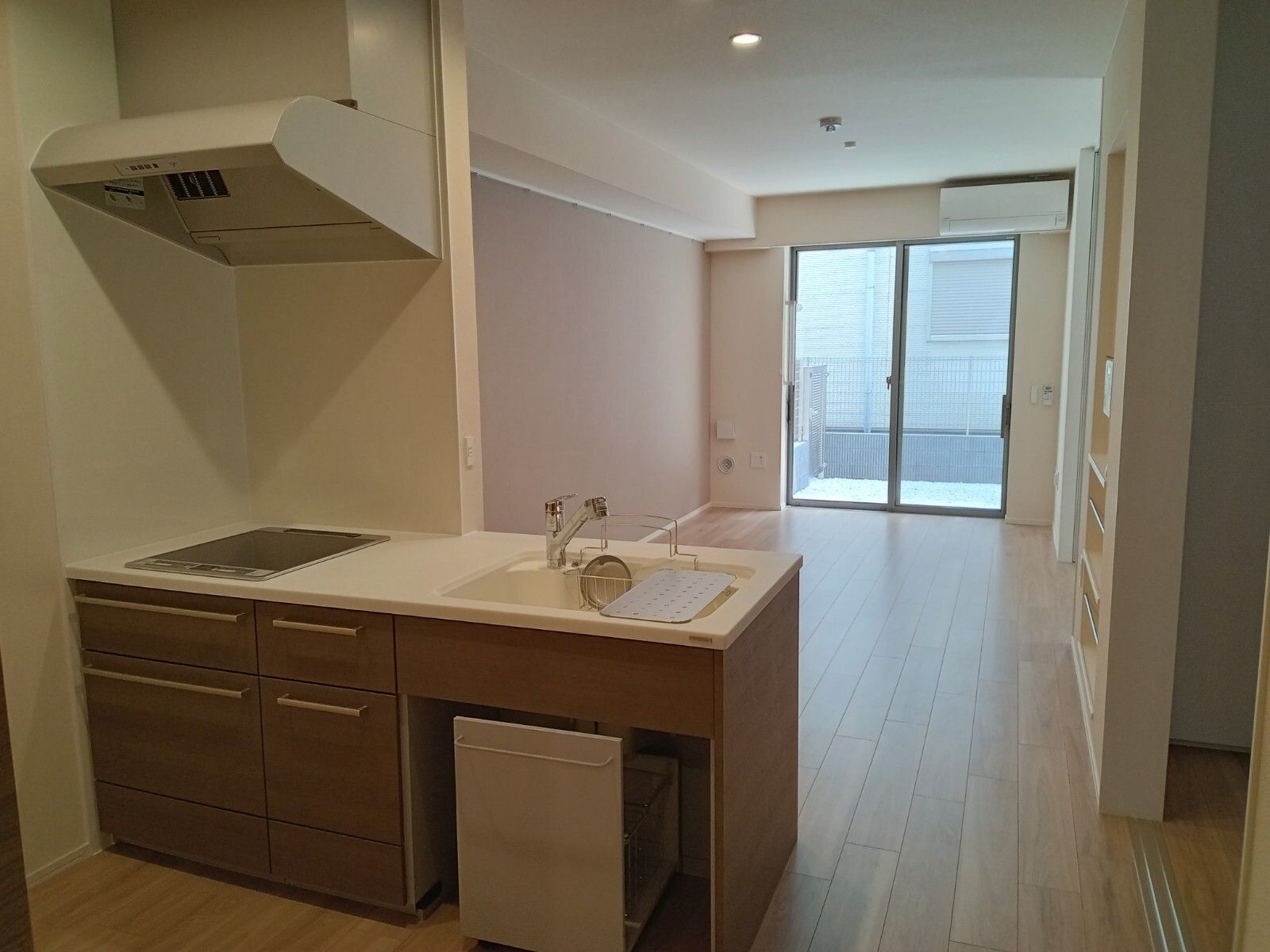 エアコンが付いたフローリングの部屋には対面式キッチンがあり、棚なども付いている。