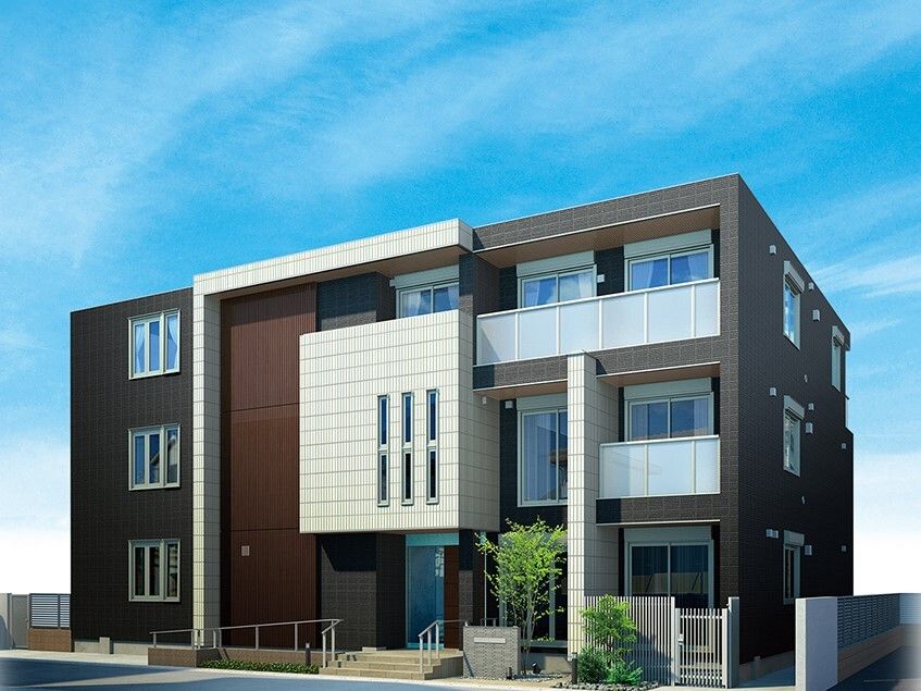 ブラウン系の3階建ての建物は日当たりのいい場所に建っていて各フロアにベランダがあり、玄関に手すり付きのスロープもある。