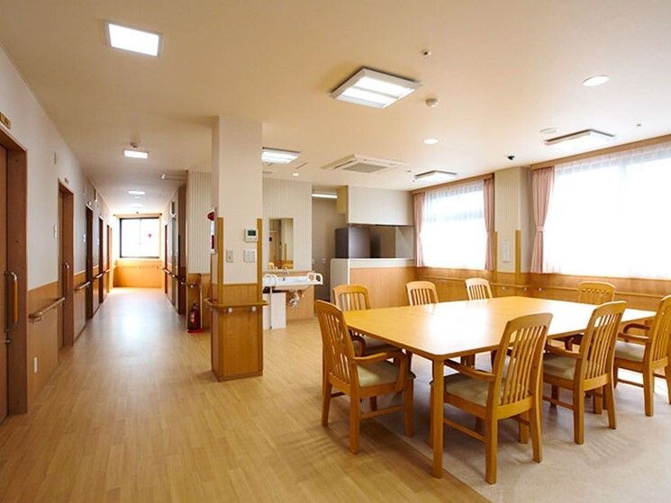 まっすぐな廊下が左側にあり、右側には木製のテーブルセットが置かれている食堂がある。