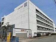 白い外壁の大きな駐車場。手前に駐車場入り口があり、外壁に駐車場名が書かれている。