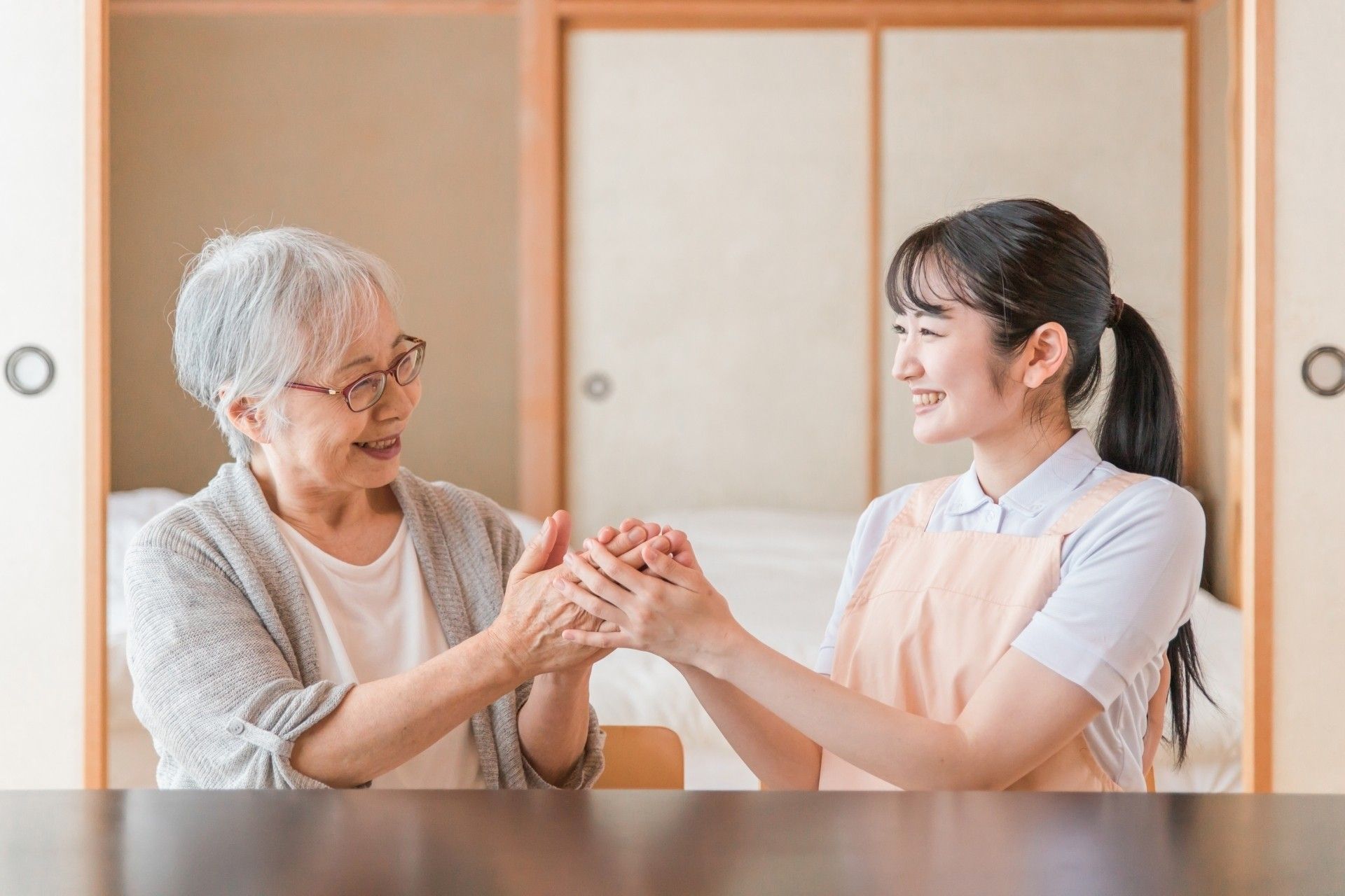 フラワーアレンジメントを楽しんでいる高齢男性を手伝っている若い女性スタッフ。