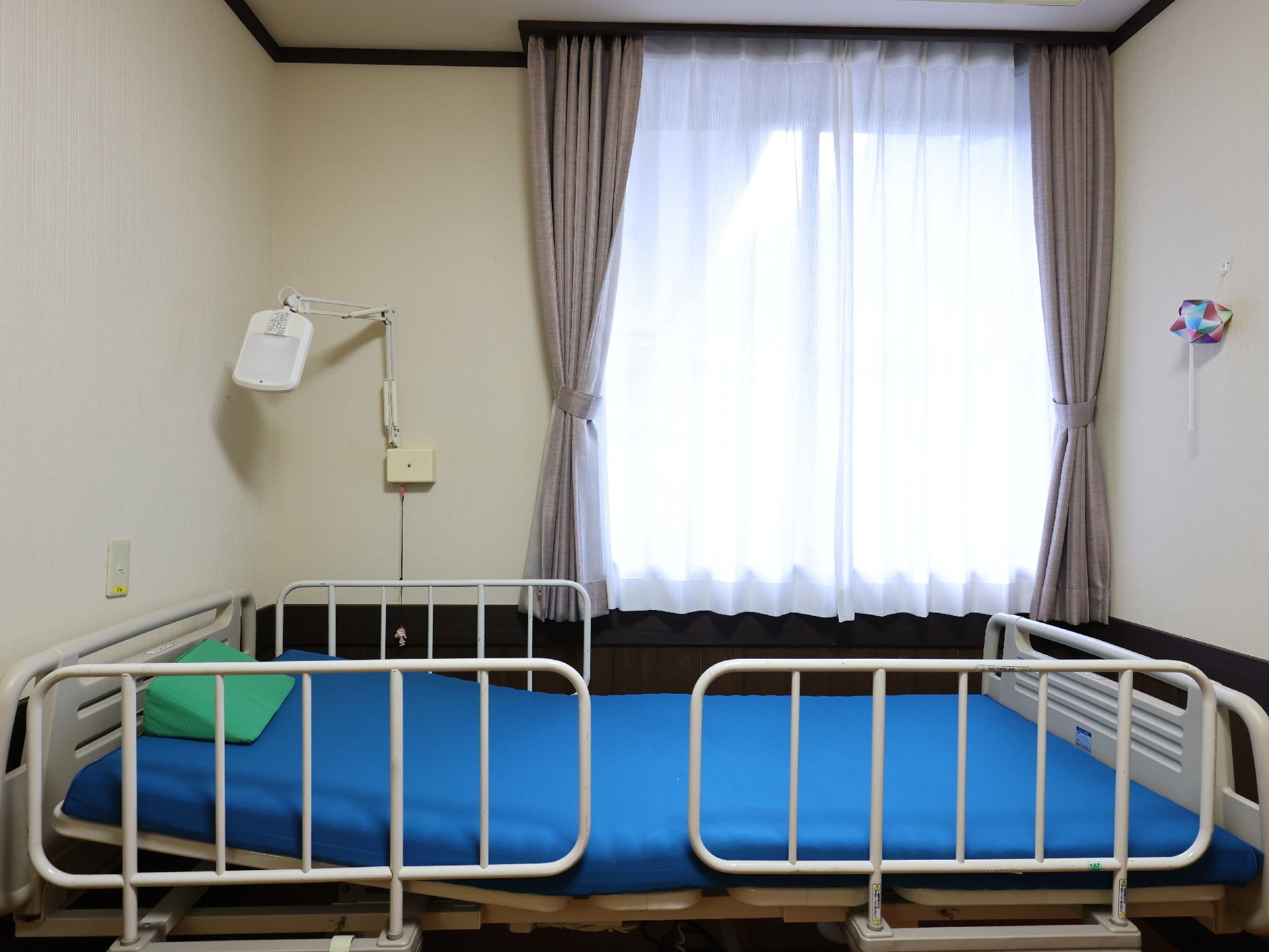 屋外で笑顔で誰かに手を振っている高齢女性と車いすを押している若い男性スタッフ。