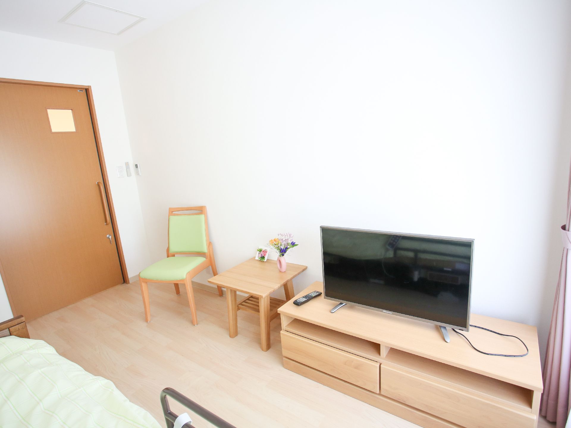 壁際にテレビと椅子が配置された白い壁の部屋