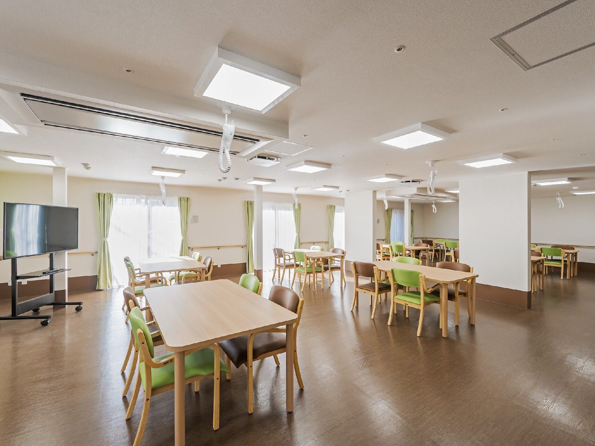 テレビが置かれている食堂にはグリーンの椅子がセットされた木製のテーブルセットが多くある。