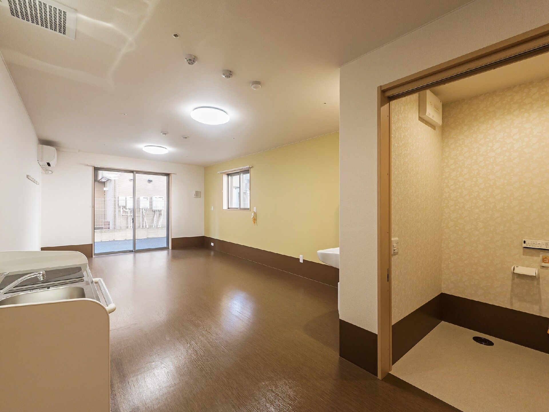 フローリングの部屋にはスライド式のドアが設置されたトイレや介護ベッドがあり、エアコンも付いている。