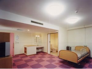 小さな棚やベッドなどが置かれた部屋には車いす対応の洗面所もある。引き戸が付いたトイレもある。