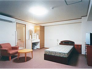浴室付きの居室にはベッドやテーブルが置かれ、車いす対応の洗面所も付いている。