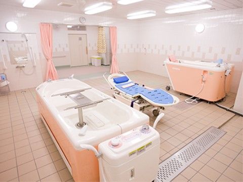 車椅子をご利用の方も快適に過ごせる空間である。ピンク色の介護浴槽とブルーのマットが敷かれた介護機器を設置している。