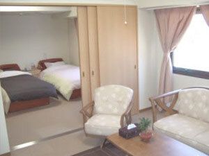 奥の部屋には寝具付きのベッドが置かれ、手前にはテーブル付きの椅子が置かれ、間には仕切りがある。
