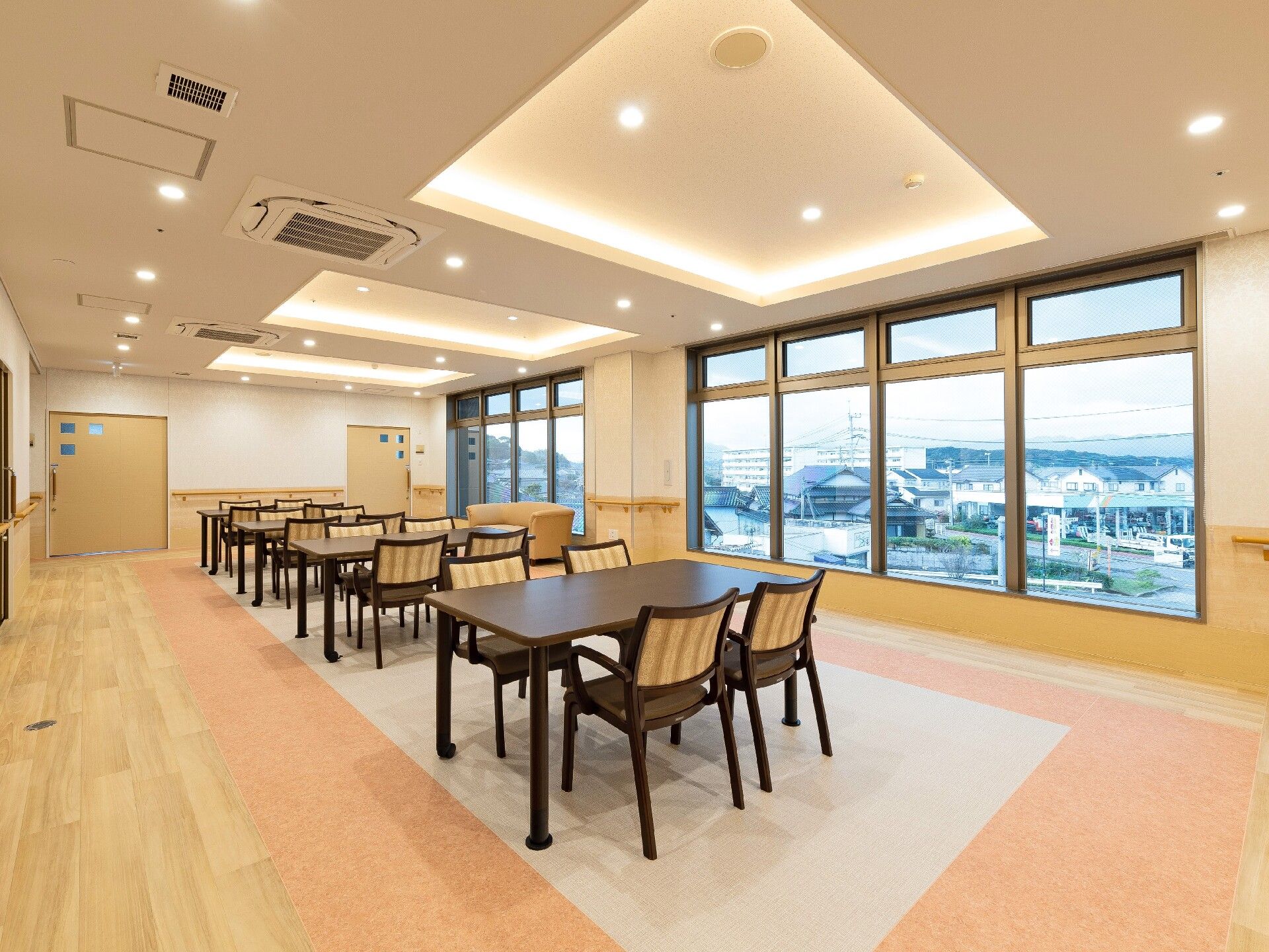 大きな窓が付いたデイサービスのフロアは壁に手すりが付き、家具や家電はまだない。