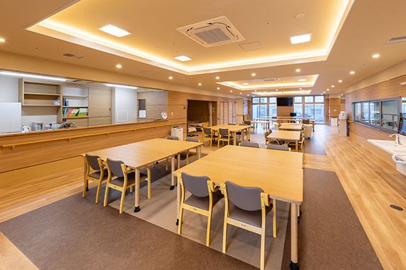突き当りの大きな窓のそばにはいすが置かれ、人の姿も見える。メインのフロアに家具はない。