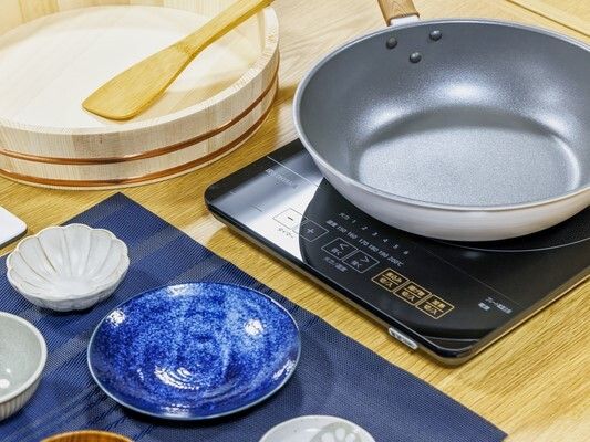 テーブルの上にはたくさんの花があり、フラワーアレンジメントを楽しんでいる高齢男性とエプロンを付けた女性スタッフがいる。