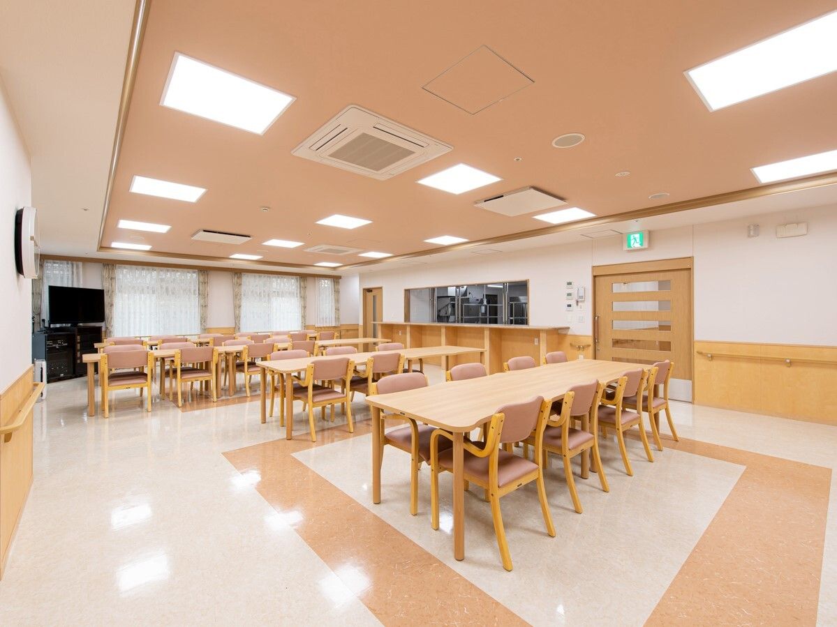 木製のダイニングテーブルセットが複数置かれた食堂には厨房があり、テレビも設置されている。