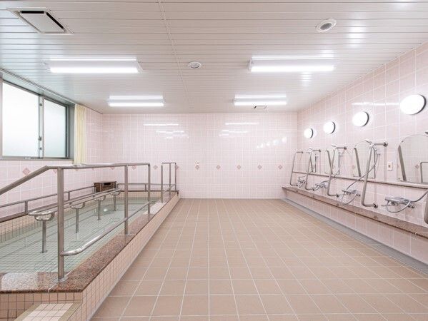 洗い場の広い大浴場。右側にはシャワースペース、左側にはたっぷりのお湯が張られている浴槽がある。
