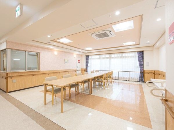 手すりが全域に設置された館内の廊下の一角にある共有スペース。木製のダイニングテーブルセットが置かれている。