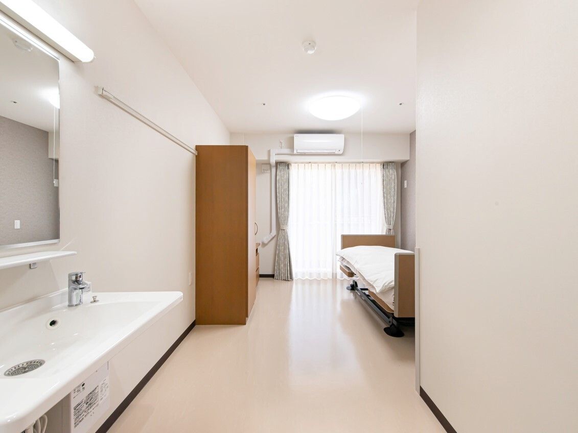 大きなクローゼット、エアコン、寝具付きのベッドがある部屋には車いす対応の洗面所が付いている。