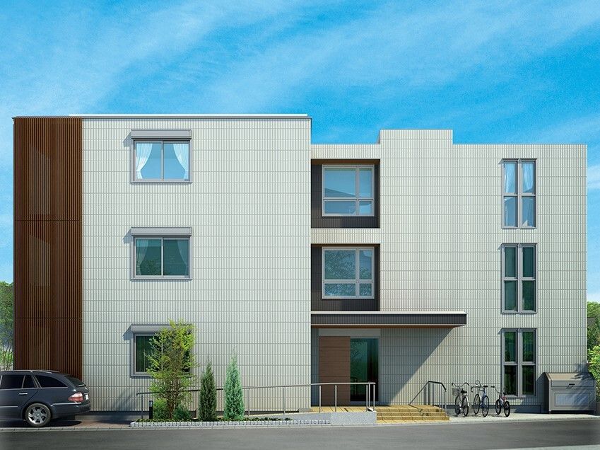3階建ての建物の玄関先には手すり付きのスロープがあり、駐輪場や駐車場もある。