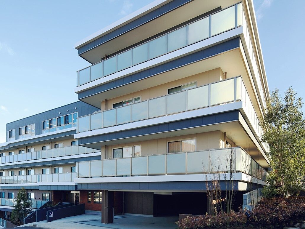 5階建ての建物はベージュとブラウン、グレー、そして白と落ち着いた色合いでまとめられている。