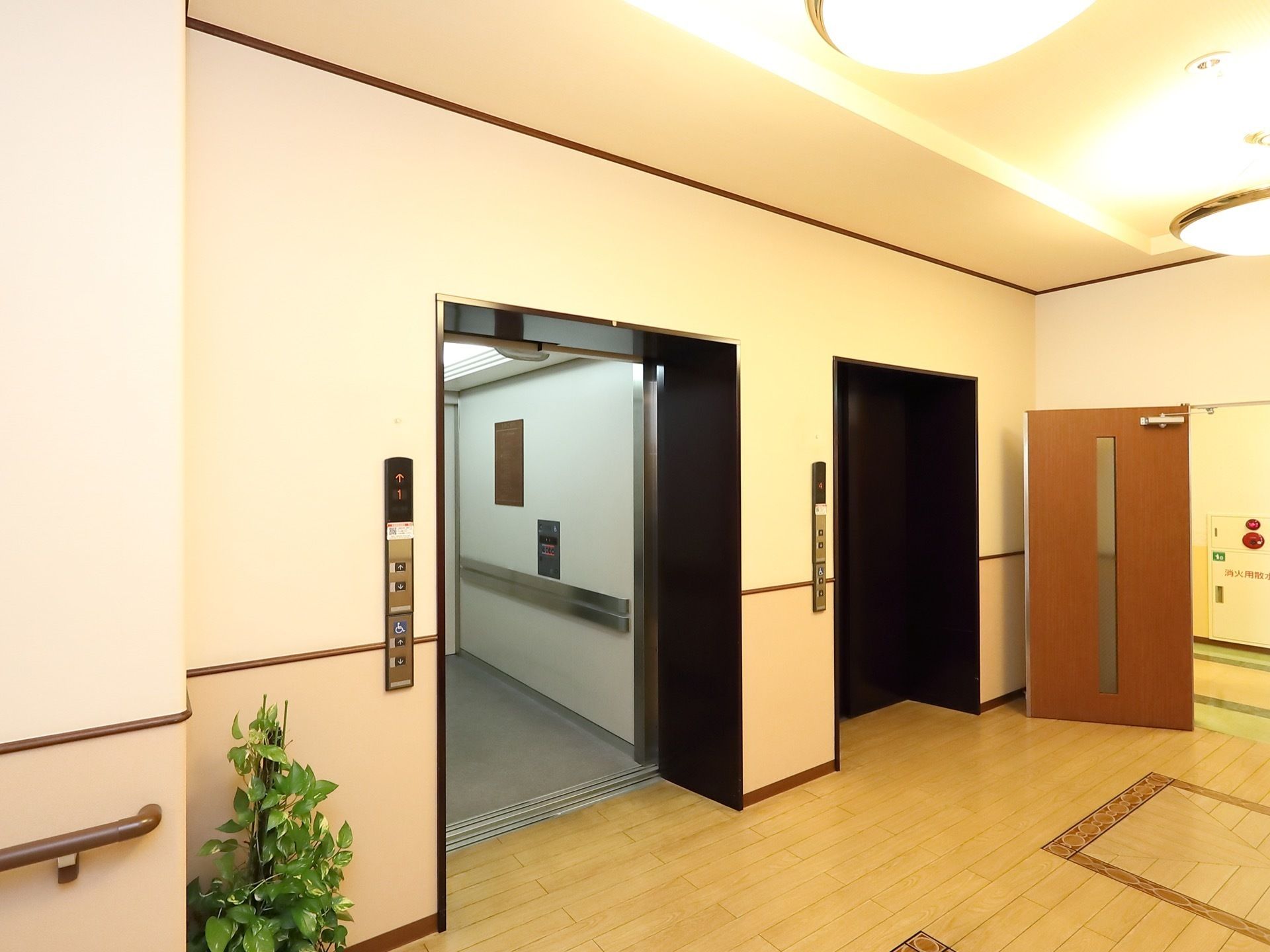 黒い扉のエレベーターが２基設置されている。中は明るく奥行きがあり、手すりや車椅子に対応した操作パネルが備えられている。