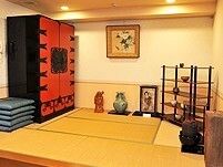 赤と黒の大きな収納家具が置かれた畳のスペースにはつぼや座布団などもある。