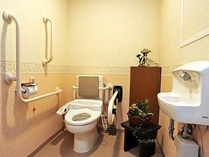 手すりがあちこちにつけられたトイレは広く、花や手洗い場もある。