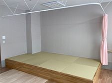 ピンクのカーテンで周りを囲むようになっている畳の小上がりスペース。カーテンは右端でまとめられている。