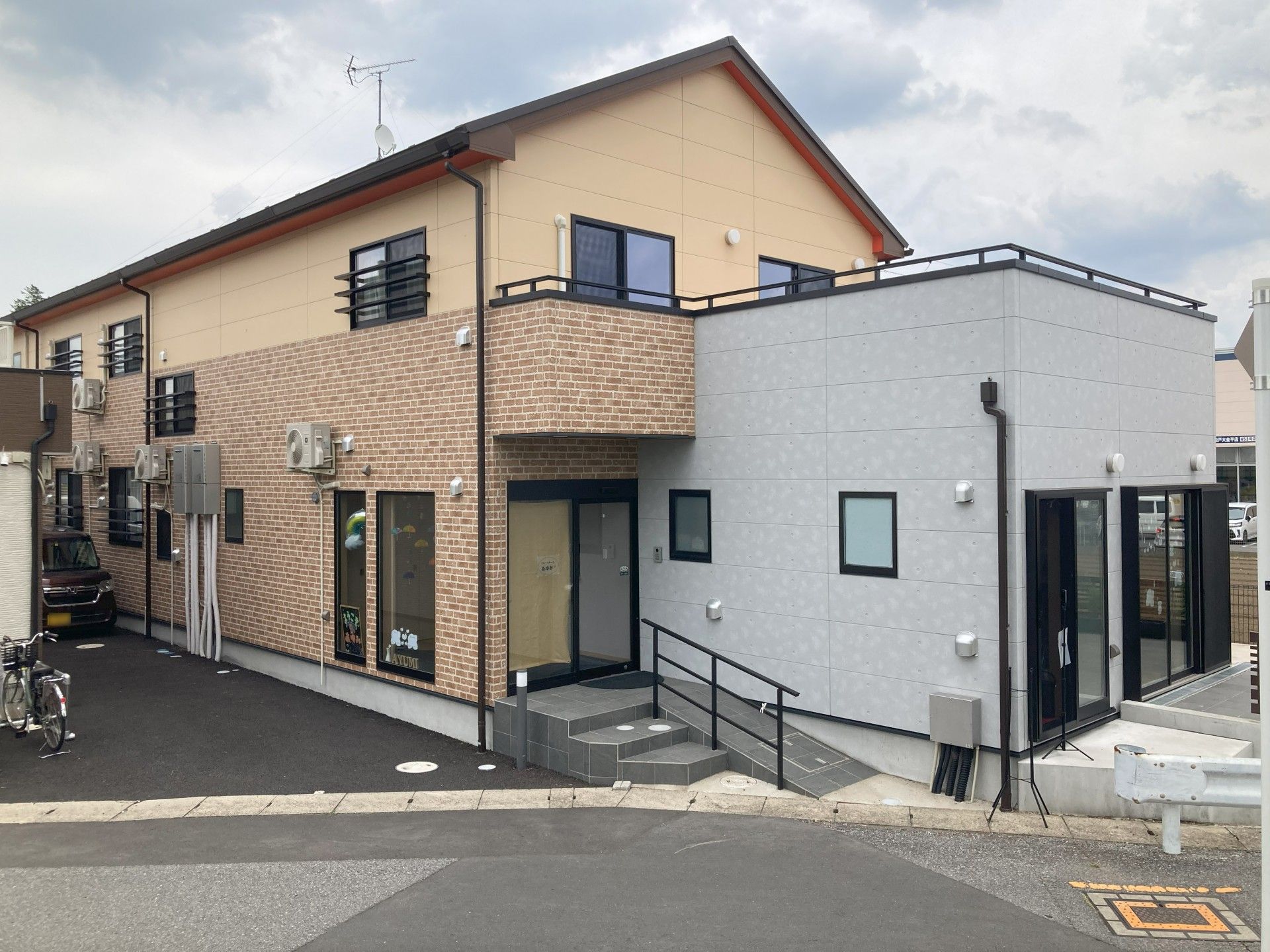 車いすの高齢女性とエプロンを付けた男性スタッフが笑顔で屋外で過ごしている。