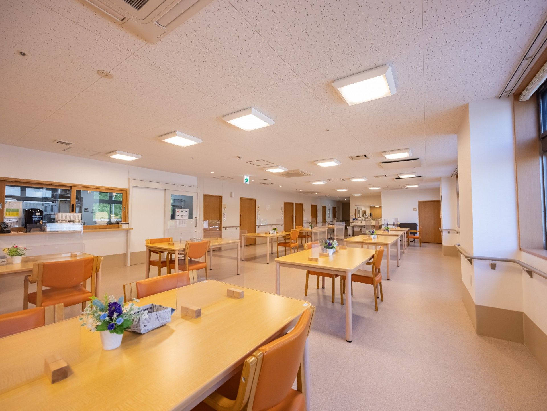 カーディガンを着た高齢女性とエプロンを付けた女性スタッフが笑顔で寄り添っている。