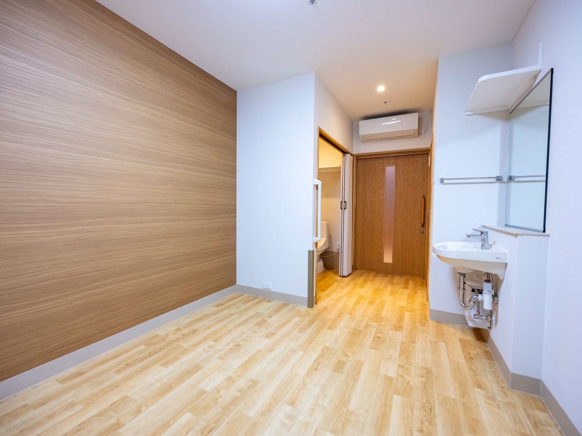 眼鏡をかけた高齢女性が車いすに座り、白衣を着た女性スタッフが車いすを押している。