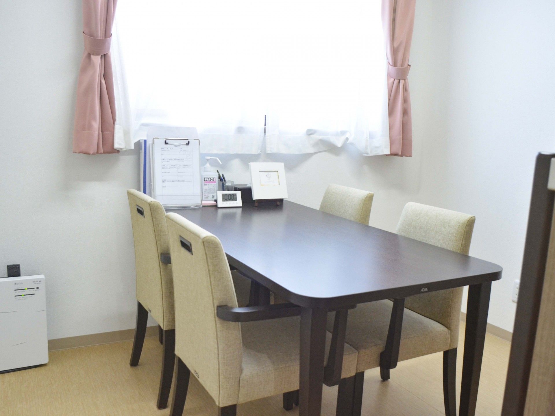 薬を飲もうとしている高齢女性のそばにはエプロンを付けた女性スタッフがいてコップを持っている。