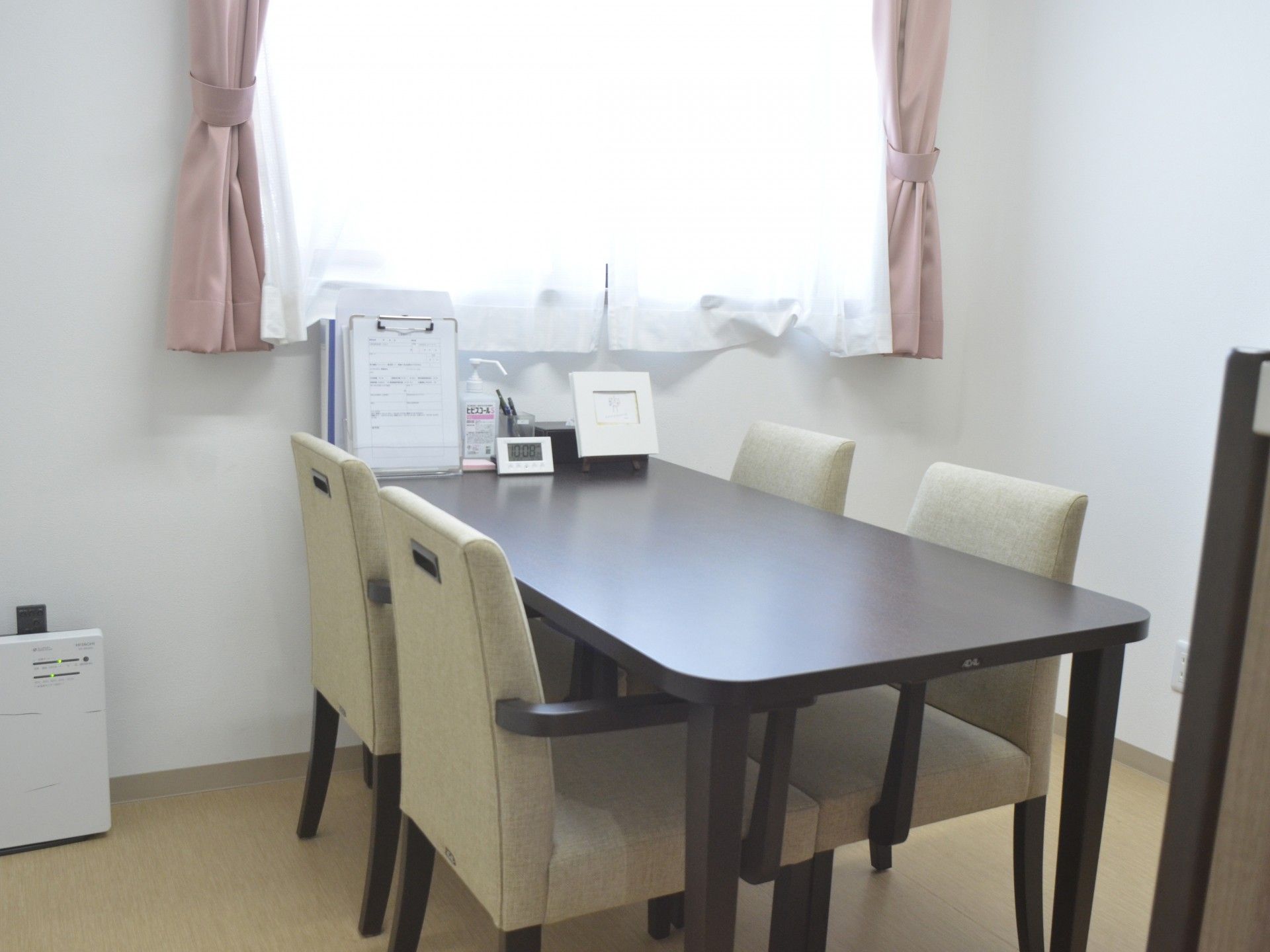 薬を飲もうとしている高齢女性のそばにはエプロンを付けた女性スタッフがいてコップを持っている。